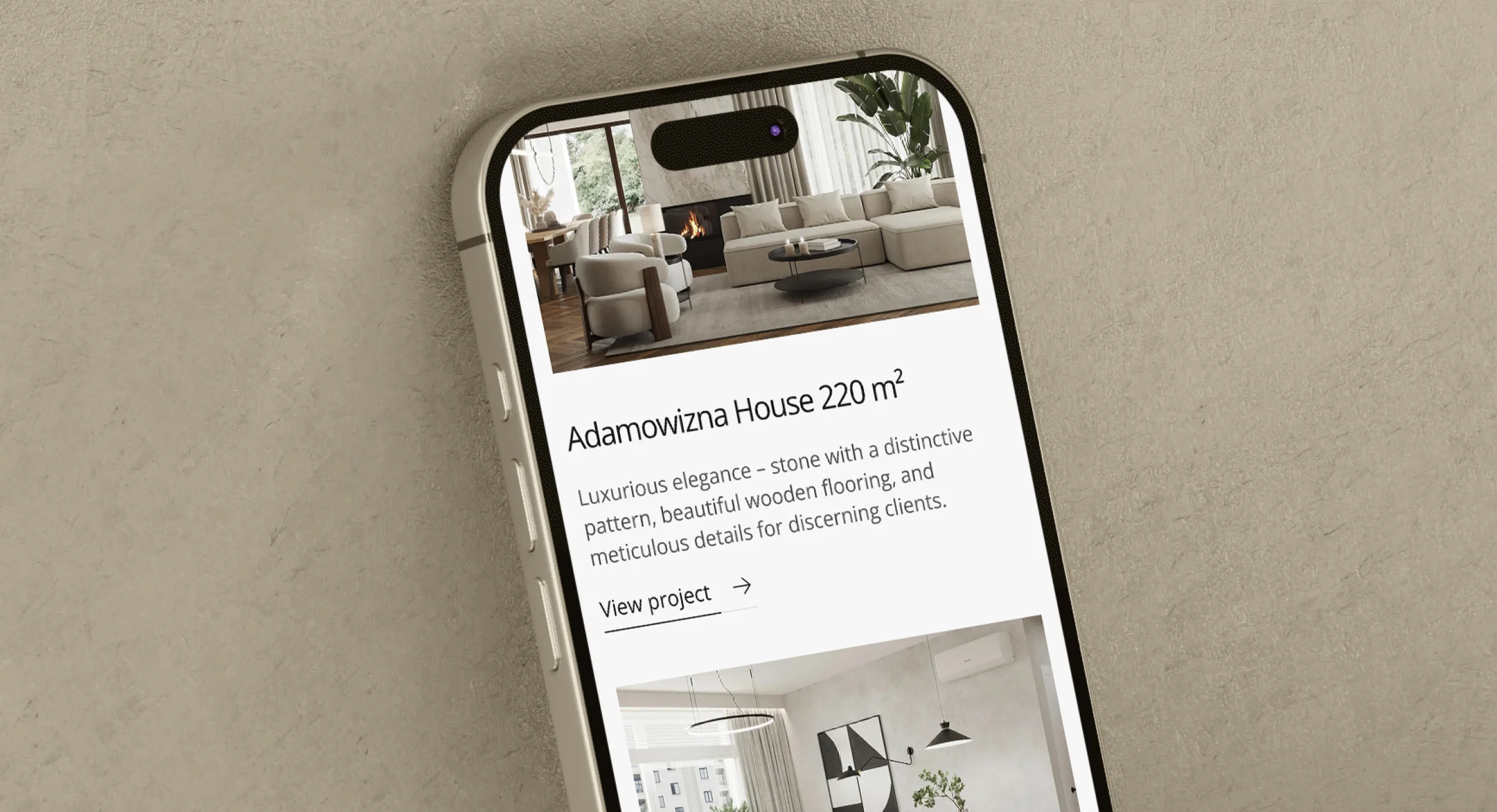 The finished site on a phone, angled against a plaster wall: the Adamowizna House project card with its 220 m² floor area in the title.
